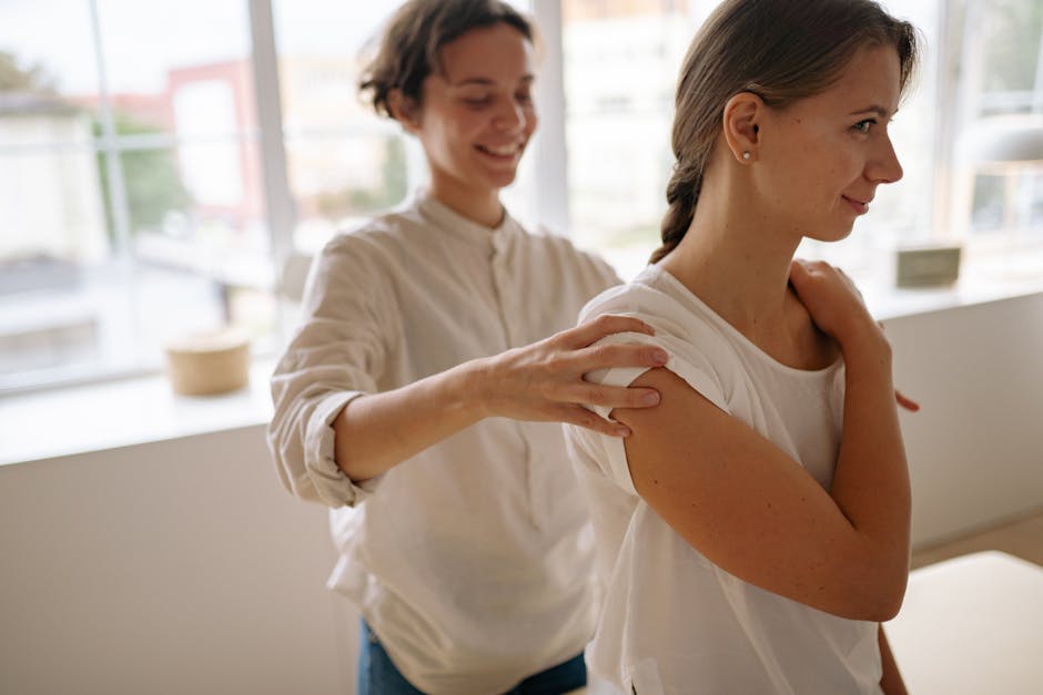 A woman receives a soothing shoulder massage in a sunlit therapy room, promoting wellness and relaxation.